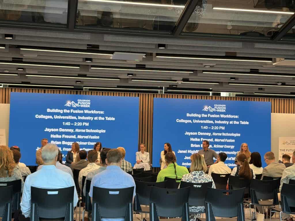 CO Fusion Week - Psyche Digital - Psyche Digital Conference stage with blue panels and event branding reading 'Colorado Fusion Week'; audience seated facing the panelists.